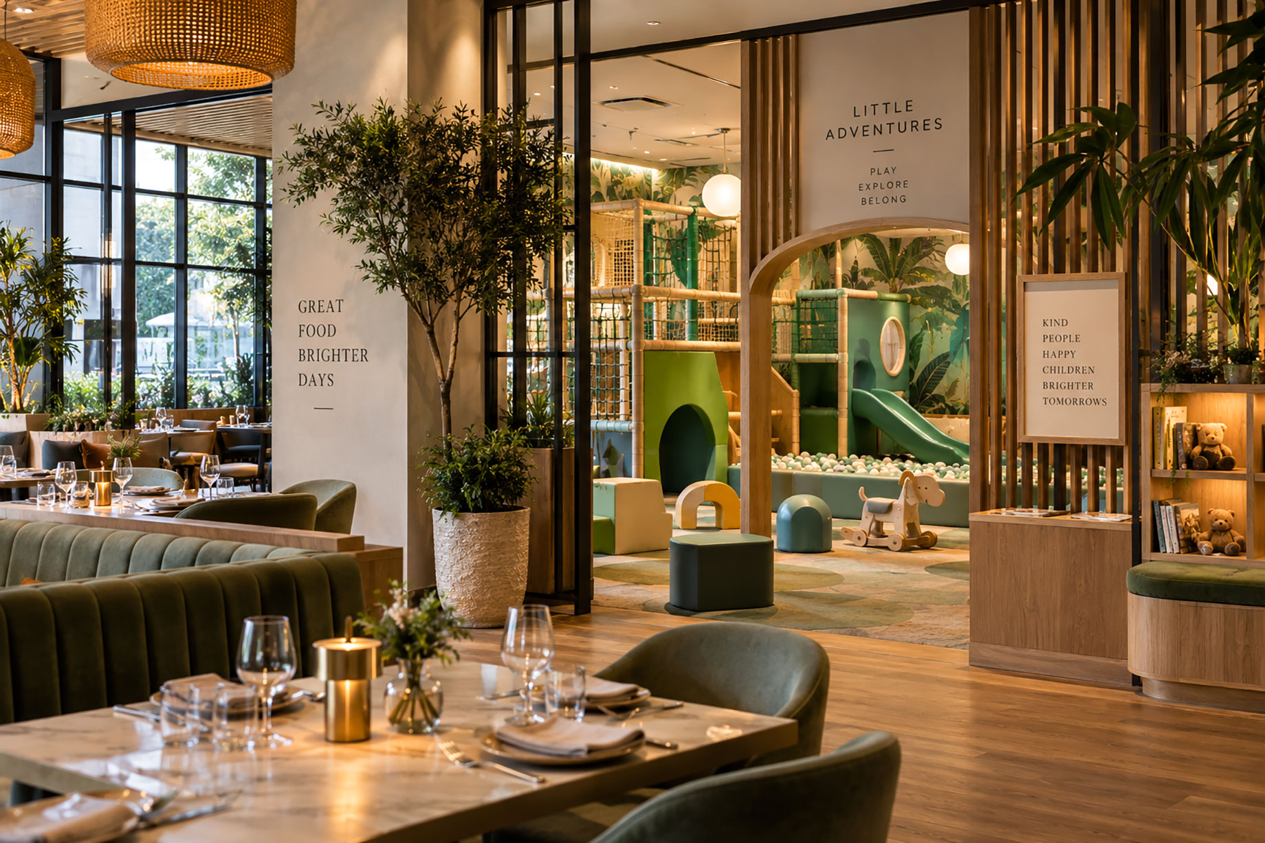 Restaurant tables and green seating beside an indoor play area with a wooden arched entrance, green slide, and ball pit.