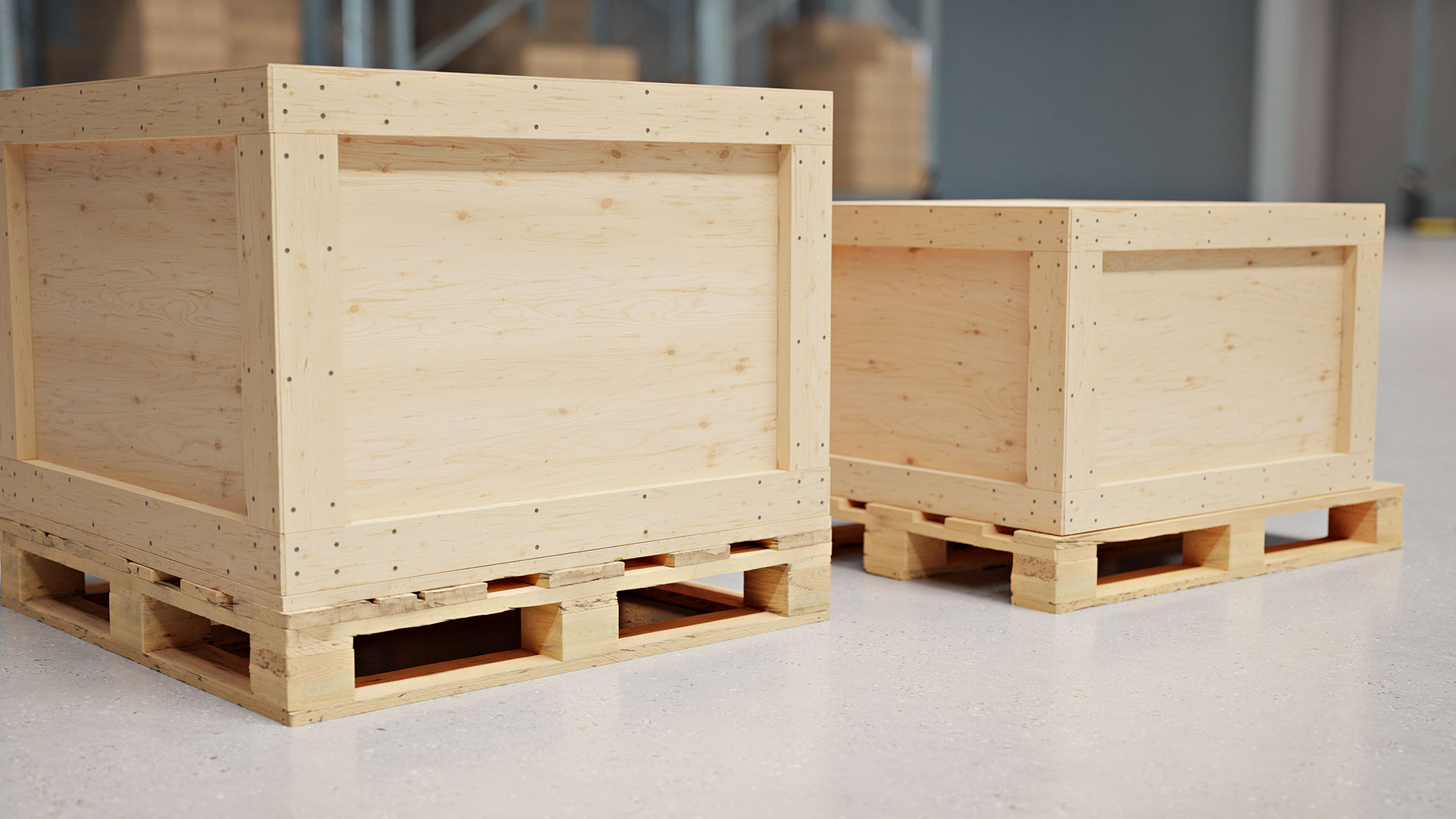 Two plywood shipping crates with timber framing and wooden pallet bases on a concrete warehouse floor.